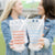 Two girls hold up their customized party pouches which read "Gameday" in a light blue and an orange font.