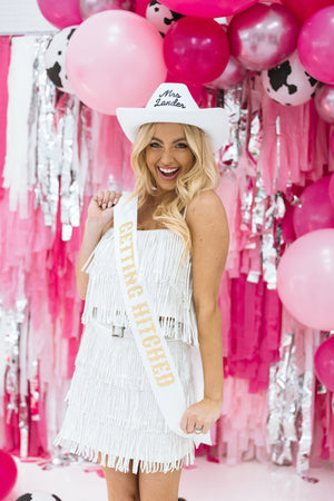 A blonde bride-to-be wears a "Getting Hitched" sash