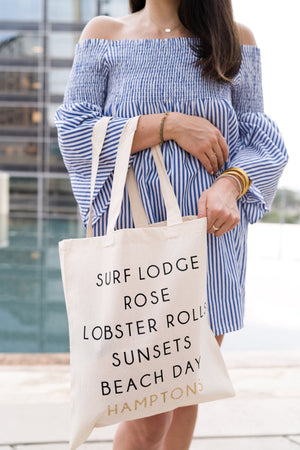 A woman holds a tote which has been customized to be the perfect bag to bring to the Hamptons.