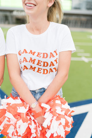 A blonde female wears a tee that says gameday while holding pompoms.