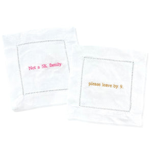 Two cocktail napkins customized with ironic phrases in pink and gold thread