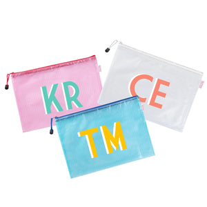 A pink, white, and a blue pouch are monogrammed with different colors.