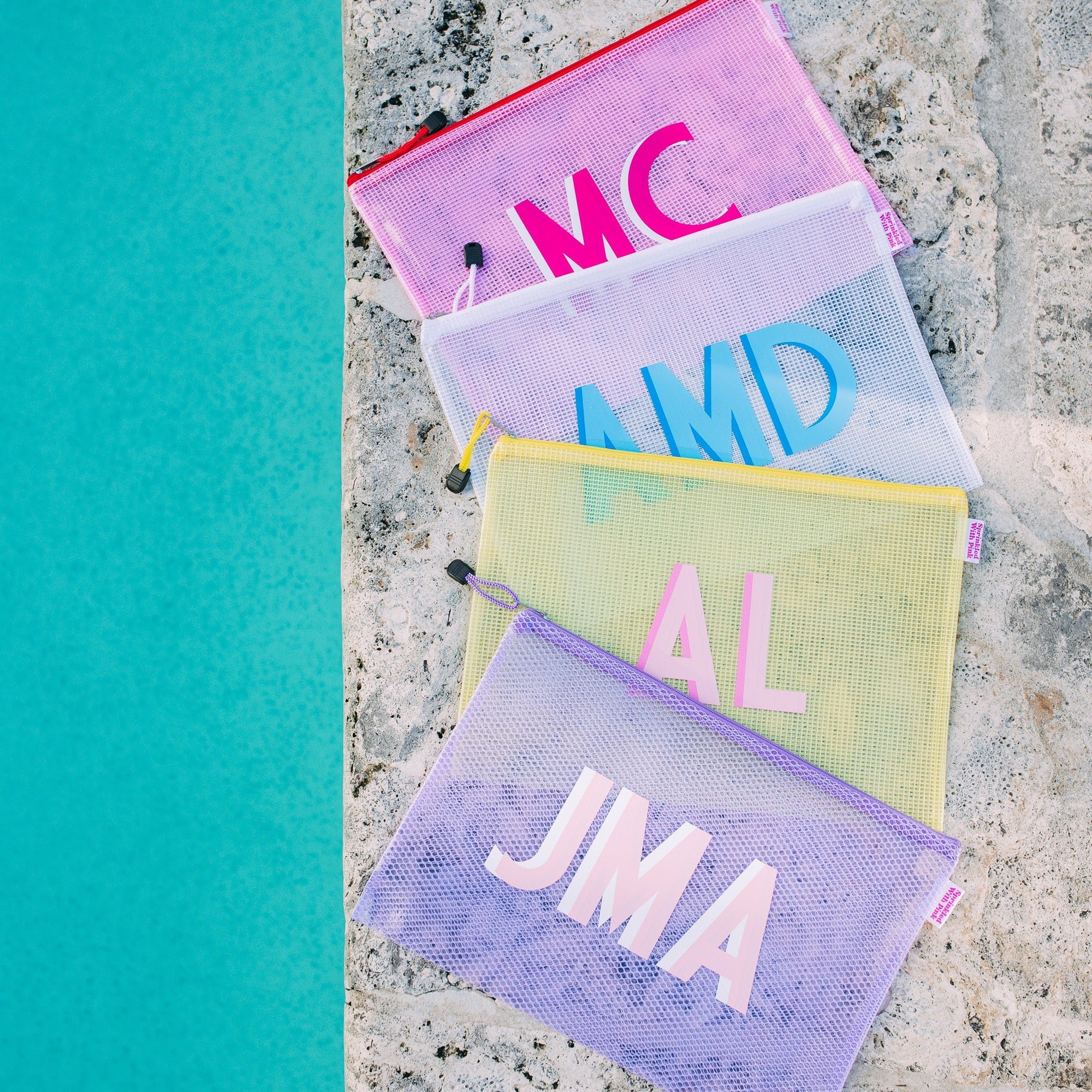A group of pool bags with colorful zippers are monogrammed with bright colors.
