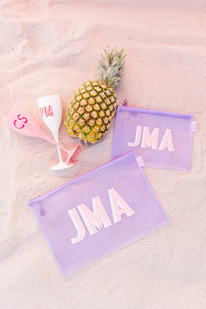 Large and small purple pool bags accompany a set of two champagne flutes and a pineapple