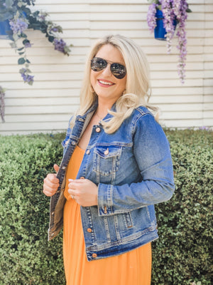 A woman in sunglasses shows off her customized denim jacket