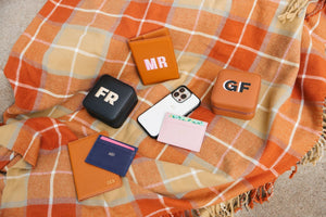Customized travel accessories sit on an orange and red flannel blanket
