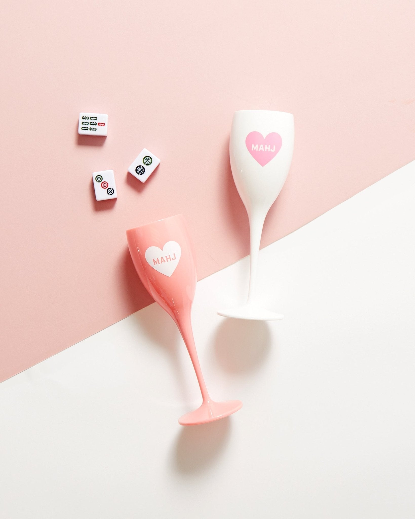 Two acrylic champagne flutes with a heart that reads "Mahj" one is white and one is pink
