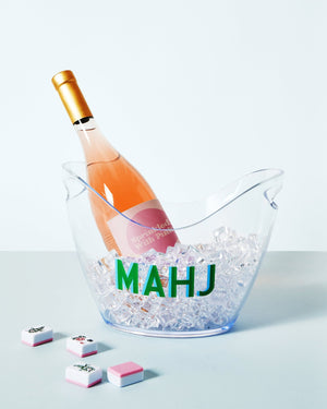 An ice bucket that reads "Mahj" with a bottle of champagne sitting on ice within