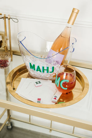 An ice bucket that reads "Mahj" with a bottle of champagne sitting on ice within