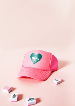 A pink trucker hat with a green heart that reads "mahj" within