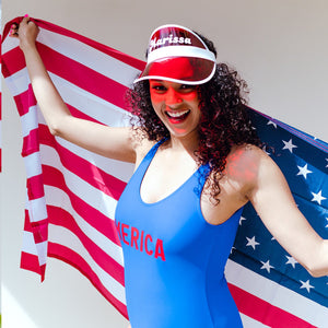 A woman holding an American flag wears a blue Merica swimsuit