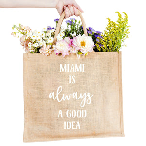 A custom jute bag reads "Miami Is Always A Good Idea" on the front