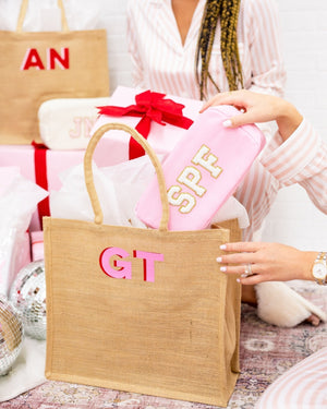 A pink pouch is placed into a monogrammed jute bag