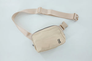 A cream colored belt bag with "LK" monogrammed on the bottom right