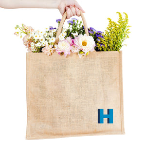 A jute tote with an "H" monogrammed on the bottom corner