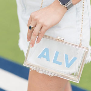 A woman wears her stadium bag customized with her initials in light blue and white.
