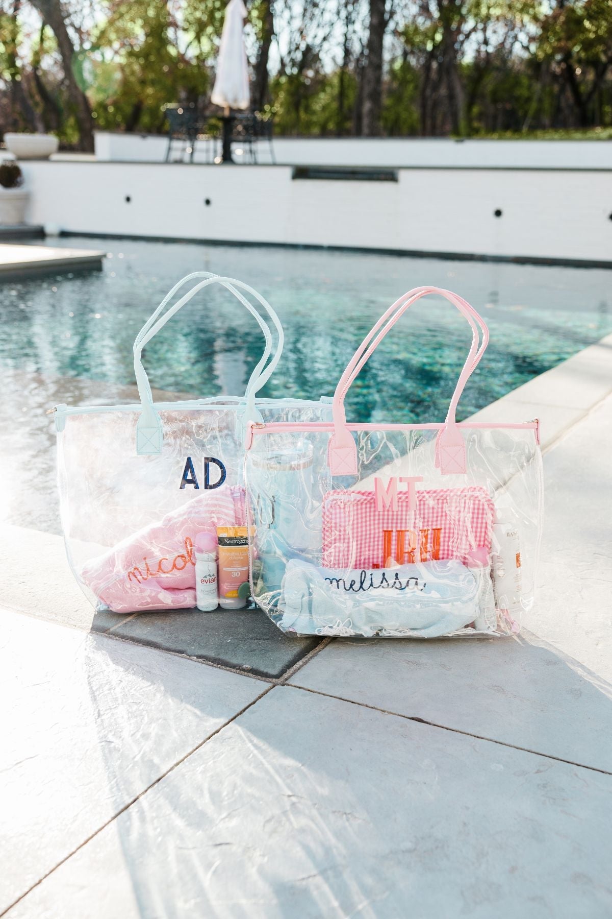 A cream, pink, and a blue clear tote are personalized with different colored monograms.