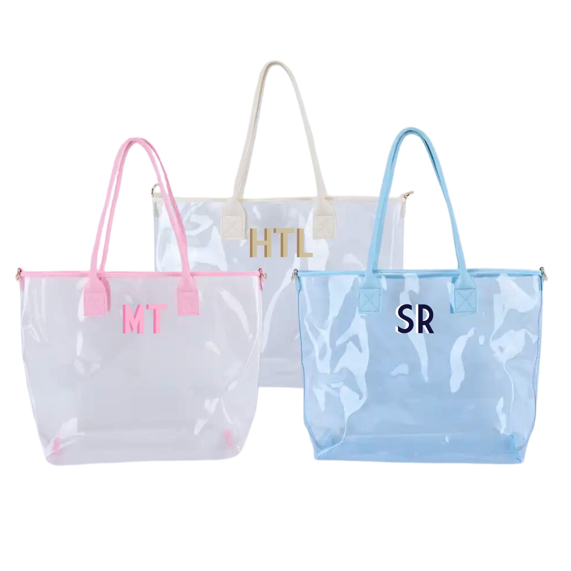 A cream, pink, and a blue clear tote are personalized with different colored monograms.