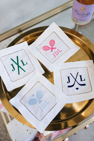 A set of four monogrammed cocktail napkins with motifs is laid out to show off some of the customization options.