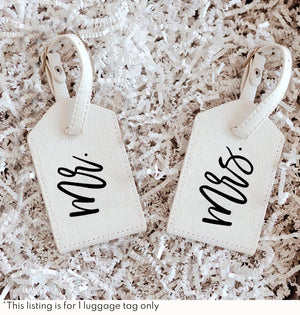 Two white luggage tags with black lettering that read "Mr. & Mrs."