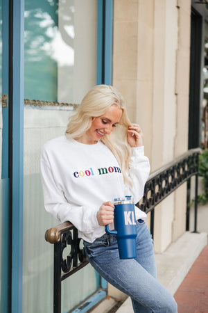A blonde wears an embroidered sweatshirt that reads "Cool Mom" in multi-colored letters