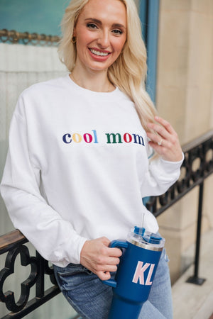 A blonde wears an embroidered sweatshirt that reads "Cool Mom" in multi-colored letters