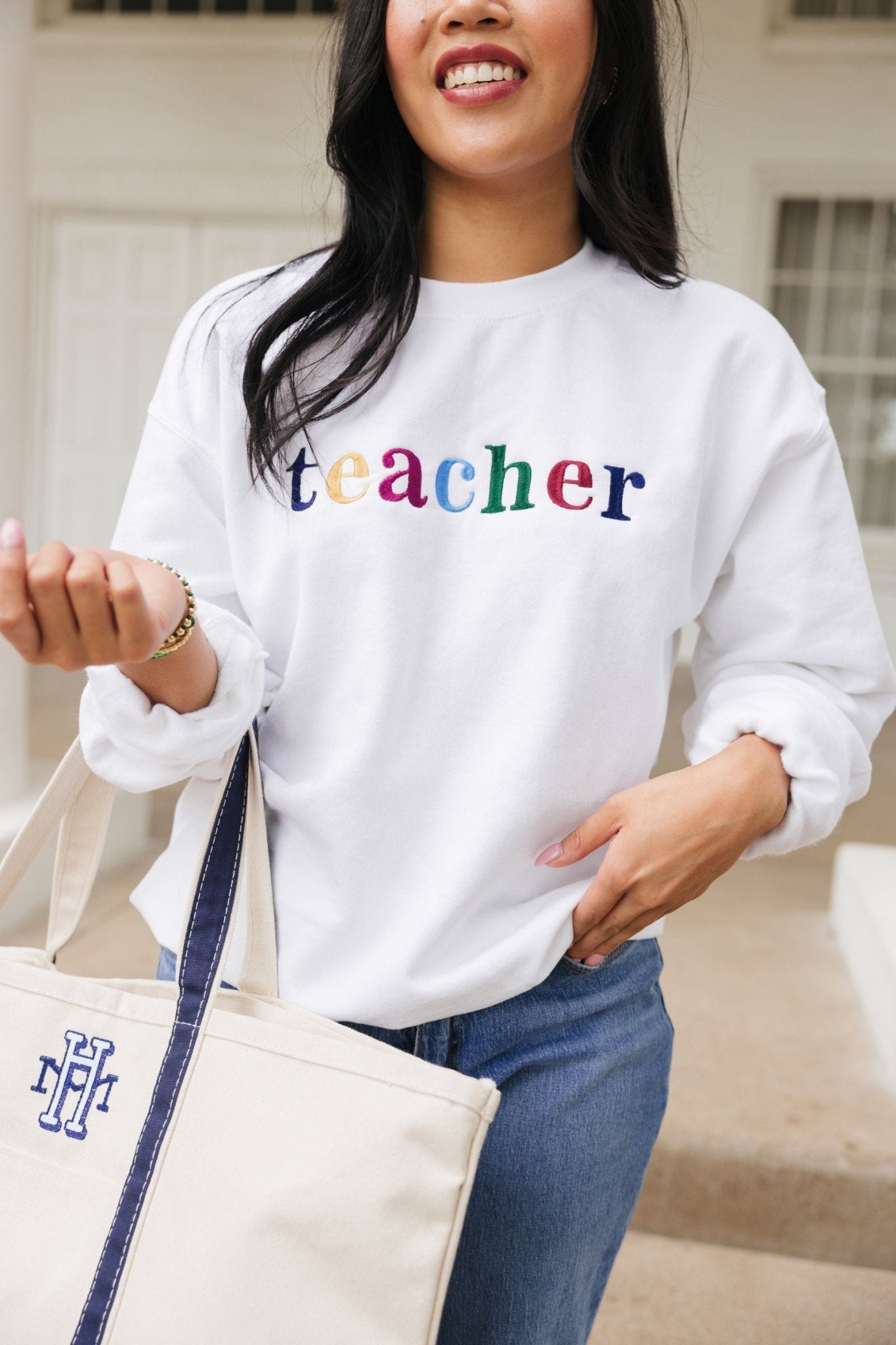 A white sweatshirt with embroidered multi-colored letters 