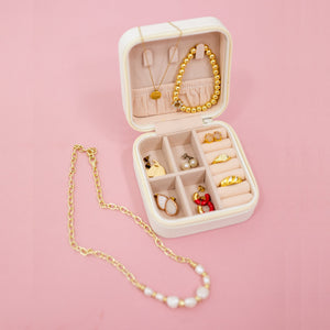 A variety of jewelry is packed into a white travel jewelry case