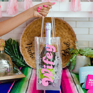 A person holds a wine bag which says "Wifey" in a pink font.