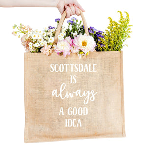 A custom jute bag reads "Scottsdale Is Always A Good Idea" on the front