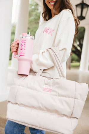 A woman holds a pink, monogrammed tumbler