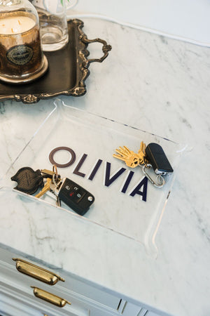 A large acrylic tray is personalized with a name and placed on a countertop along with 2 sets of keys.