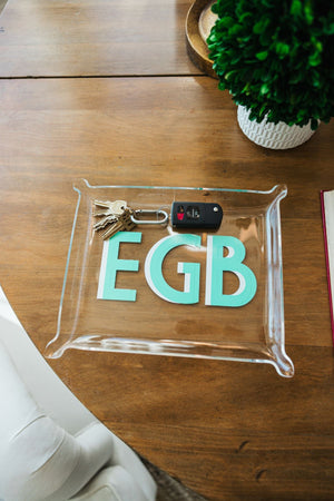 An acrylic tray with a set of keys inside is personalized with a mint and white monogram.