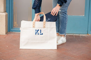A woman puts a custom pouch into her monogrammed weekender bag