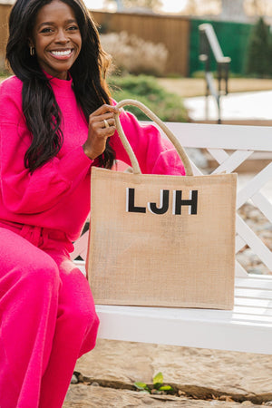 A girl in a pink set reaches into her personalized jute tote.