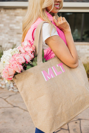 A girl holds her personalized tote bag which is filled with some pink and white flowers.