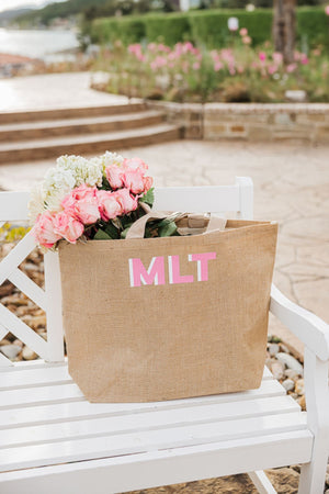 A personalized tote bag is filled with some pink and white flowers.