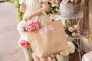 A woman holds a custom monogrammed jute bag filled with pink and white flowers