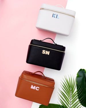 A white, black and tan train case are customized with colorful monograms across the front.