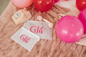 A set of custom small and large pool bags are laid out next to some balloons and a pink telephone.