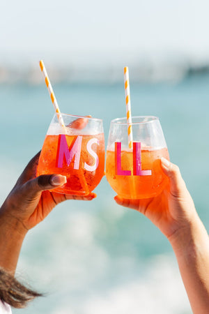 Two females clink their monogrammed wine tumblers on the beach