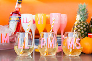 Stemless wine glasses with a custom shadow monogram sit next to fruits and Aperol