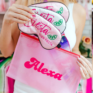 A person holds up 3 sleep masks that have been customized with "Siesta then Fiesta" and a pink pouch with a name printed on it.