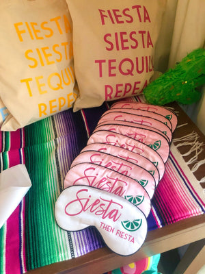 A group of pink and white sleep masks are customized to read "Siesta then Fiesta".