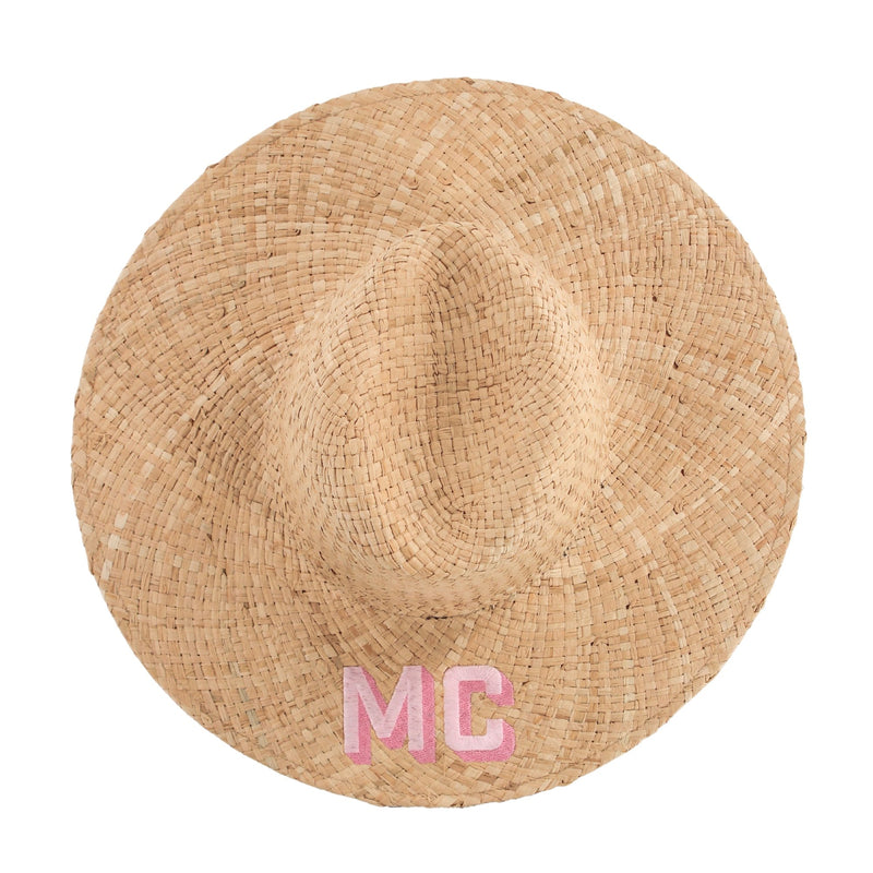 A straw beach hat with "MC" embroidered on the brim