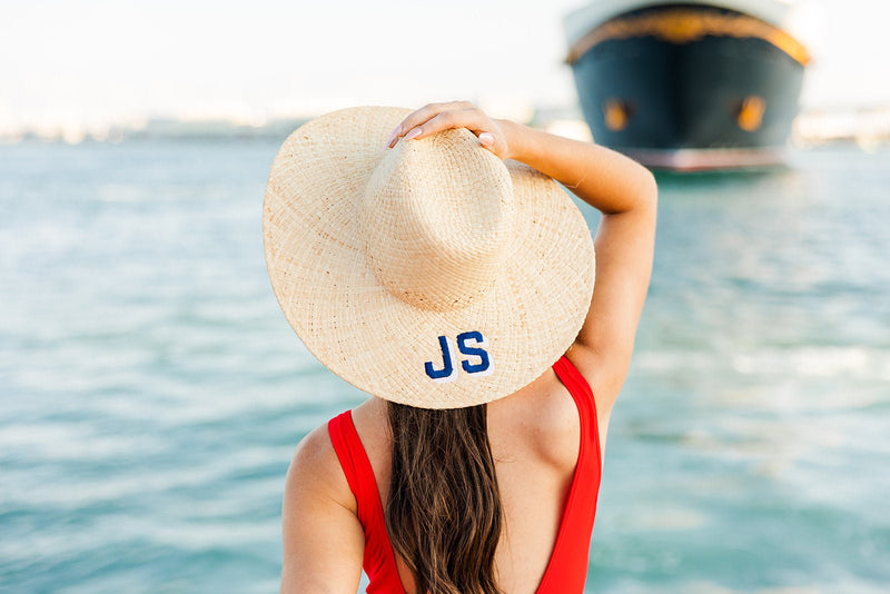 A brunette wears a beach hat with an embroidered monogram