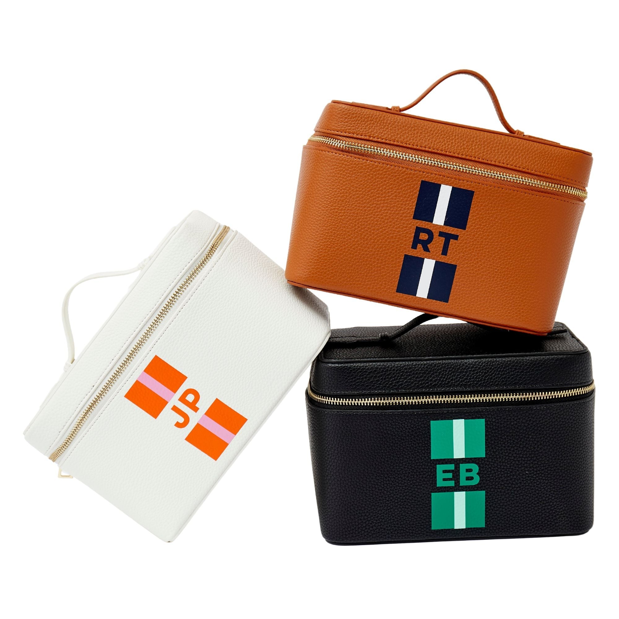 A group of white, tan, and black train cases are personalized with colorful stripe monograms.