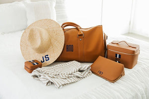  An array of tan leather travel accessories are customized with navy monograms.