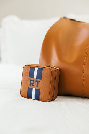 A tan jewelry case is customized with a blue and white stripe and monogram.