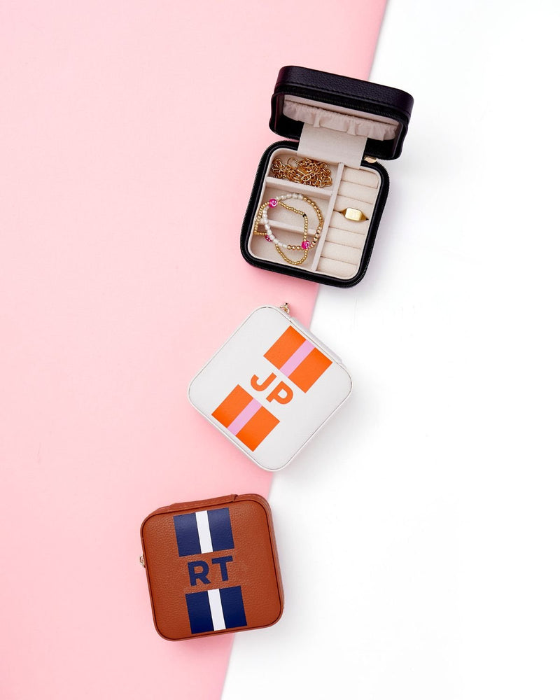 A black, white, and tan jewelry case are customized with monograms and a stripe design.